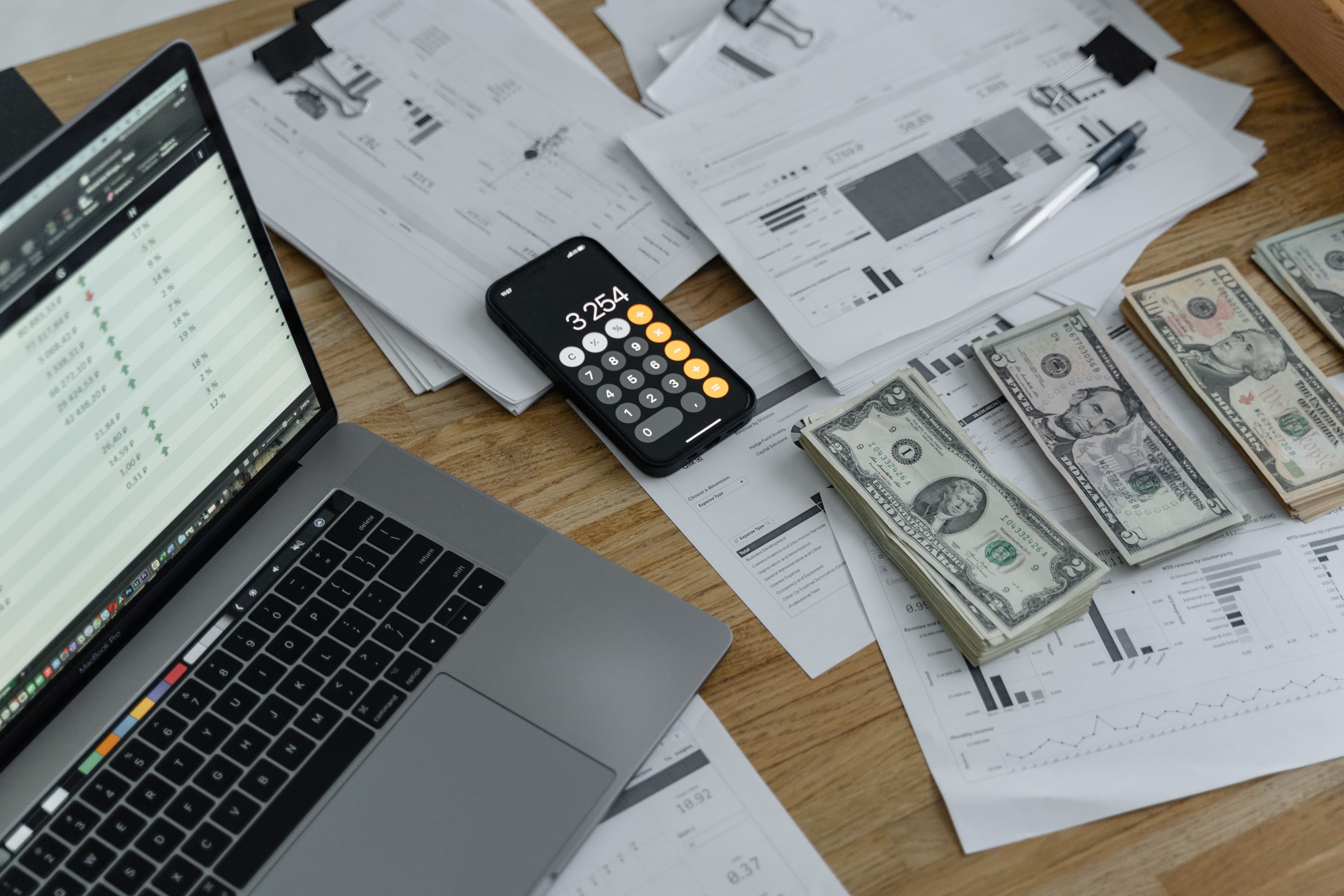 Mesa com documentos financeiros, calculadora e notebook
