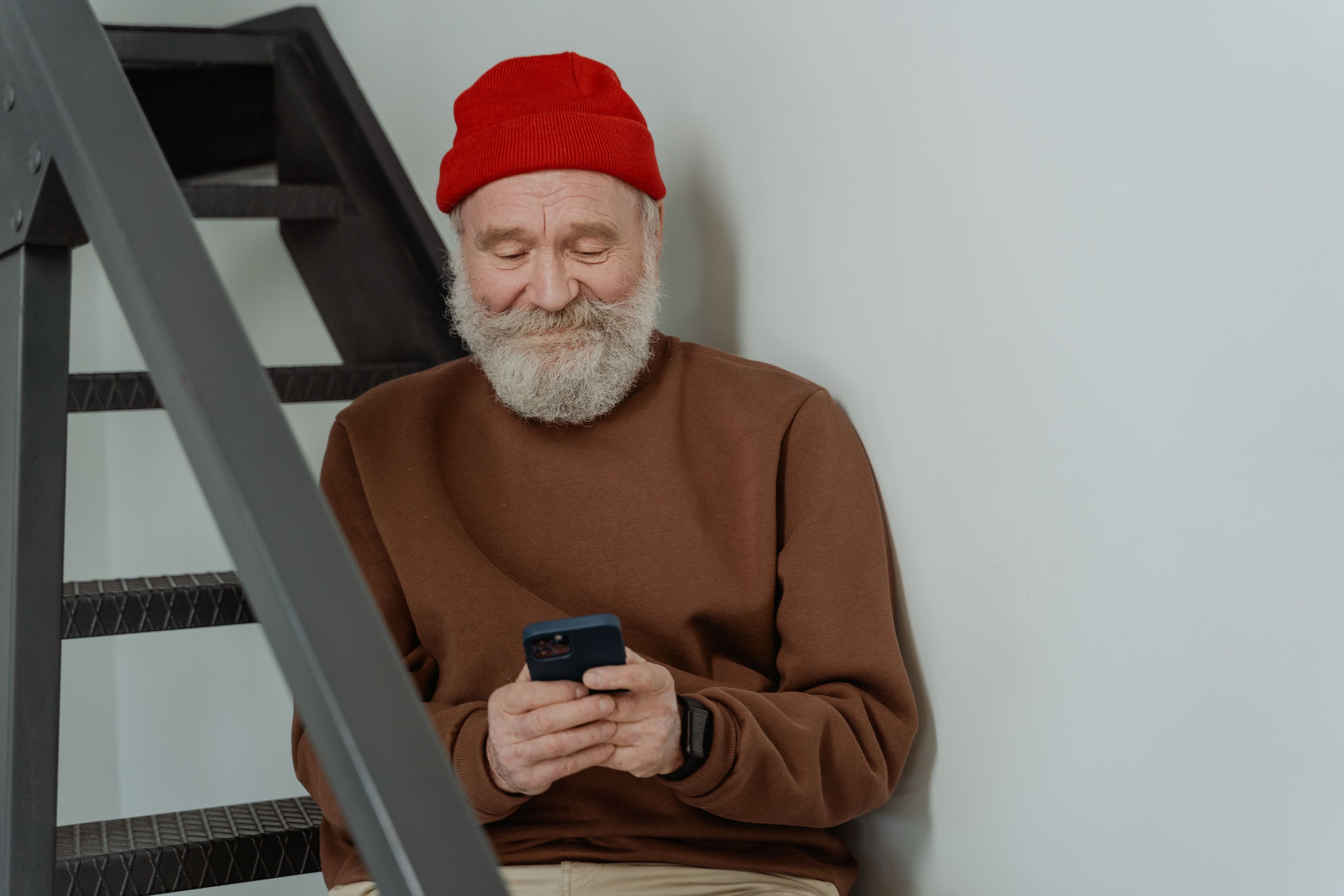 Pessoa idosa sentada no sofá usando o celular para acessar o aplicativo Meu INSS