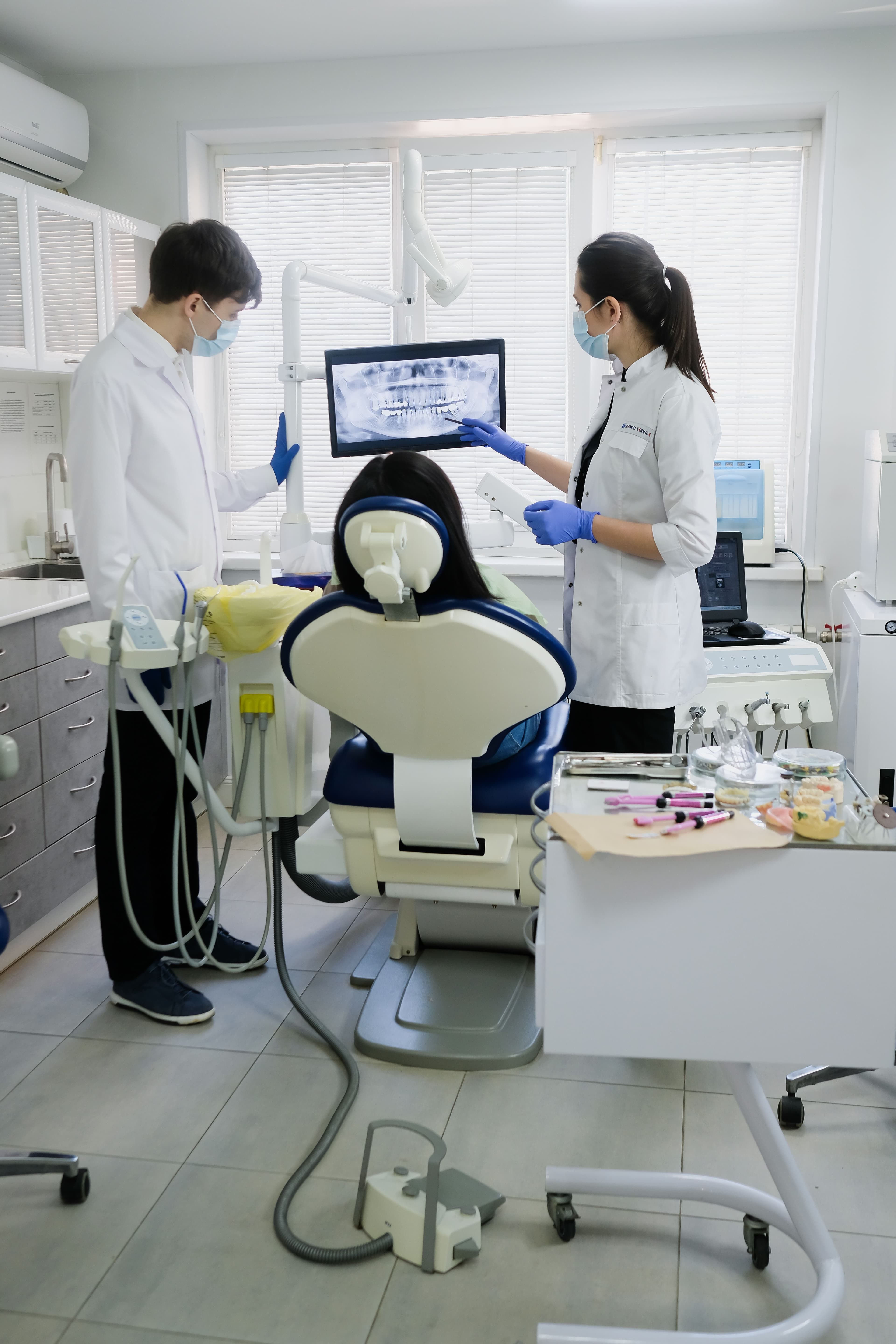 Equipe odontológica examinando paciente em consultório moderno, com equipamentos de proteção