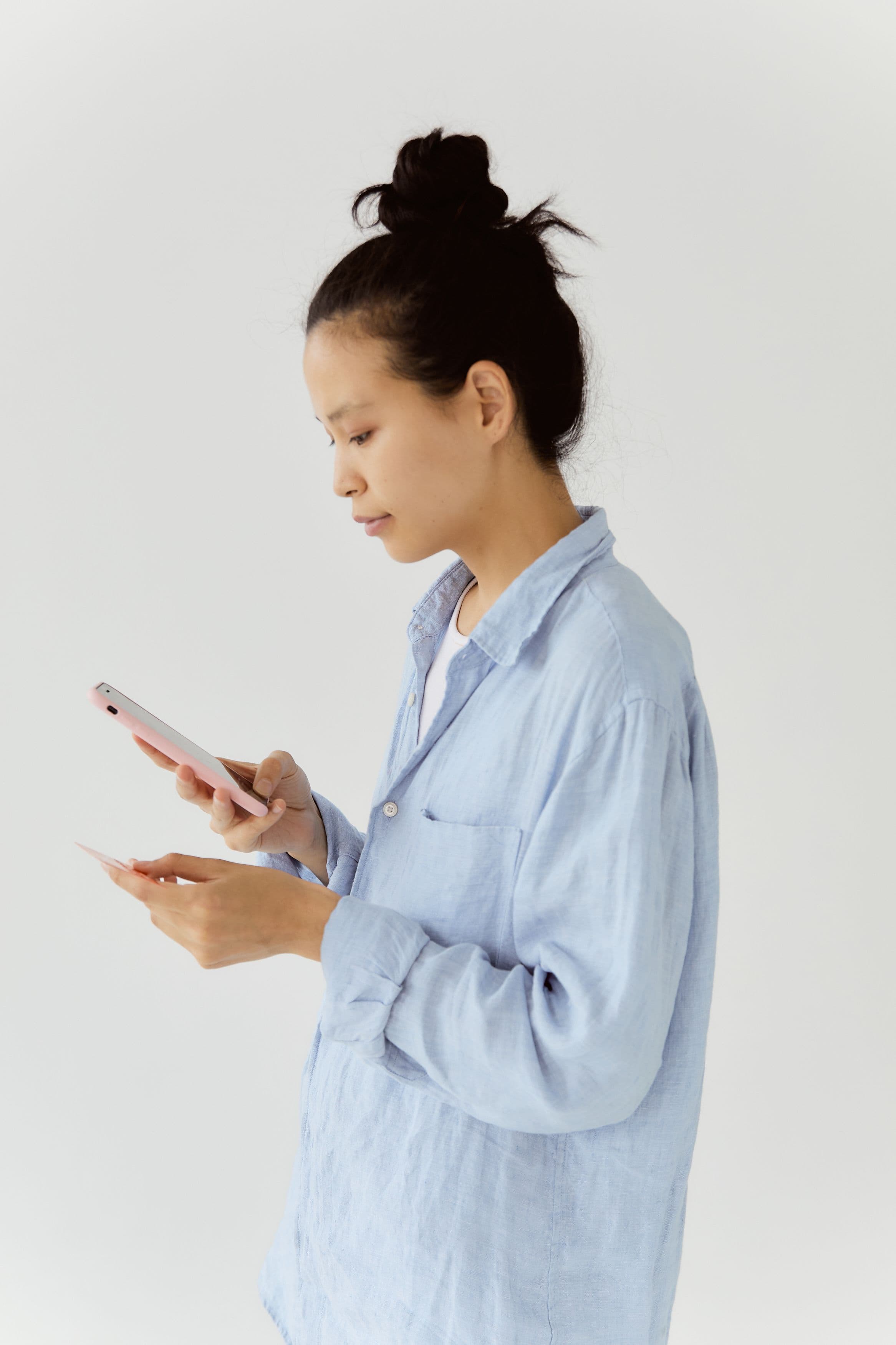 Mulher verificando situação de crédito no smartphone com cartão na mão