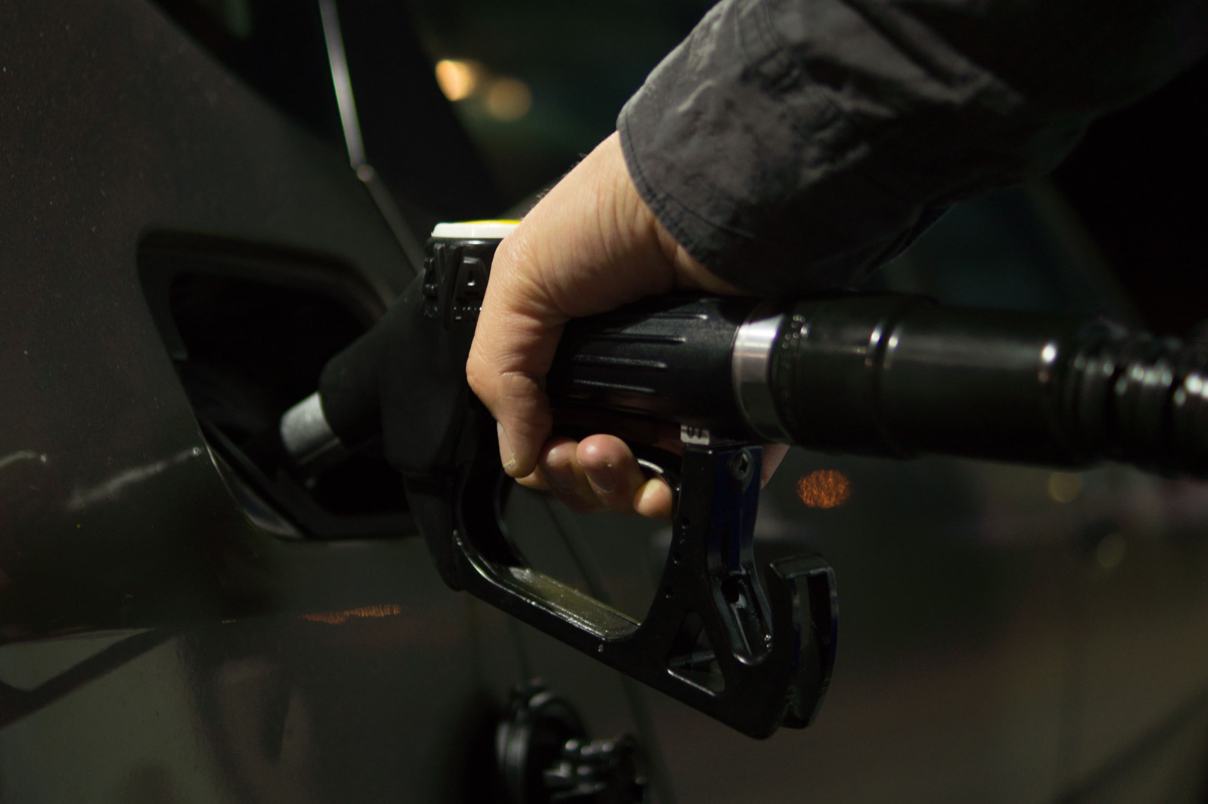 Frentista abastecendo veículo com mangueira de combustível em posto de gasolina