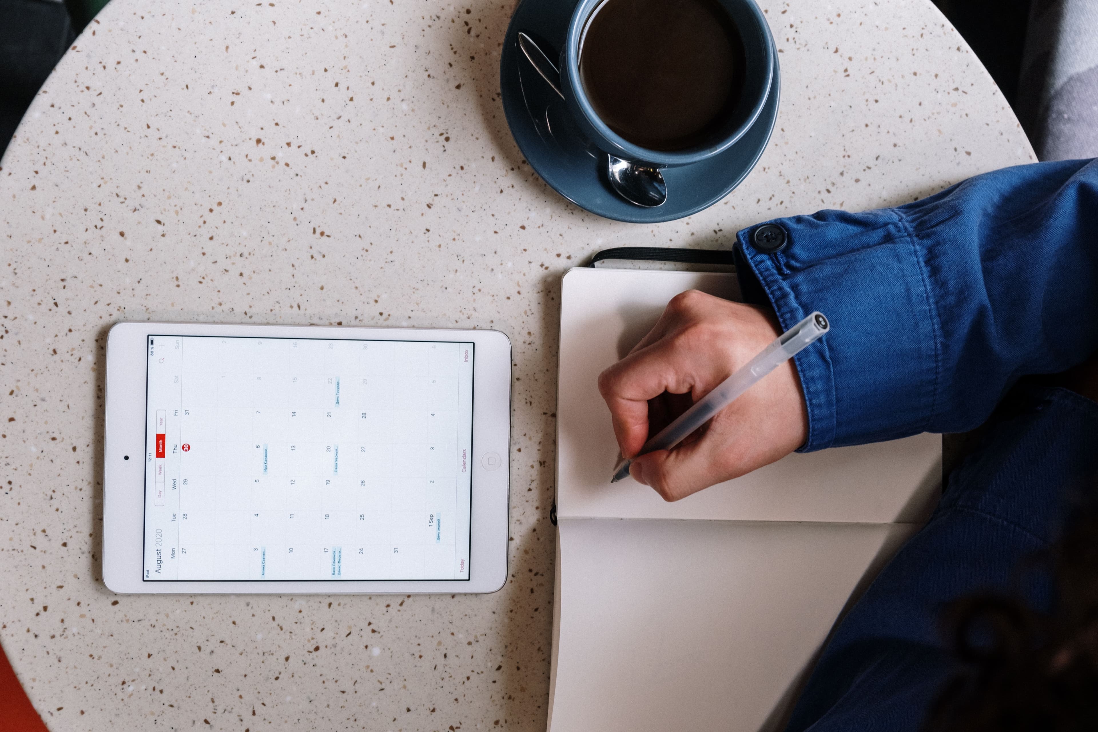 Pessoa segurando caneta e consultando calendário em tablet